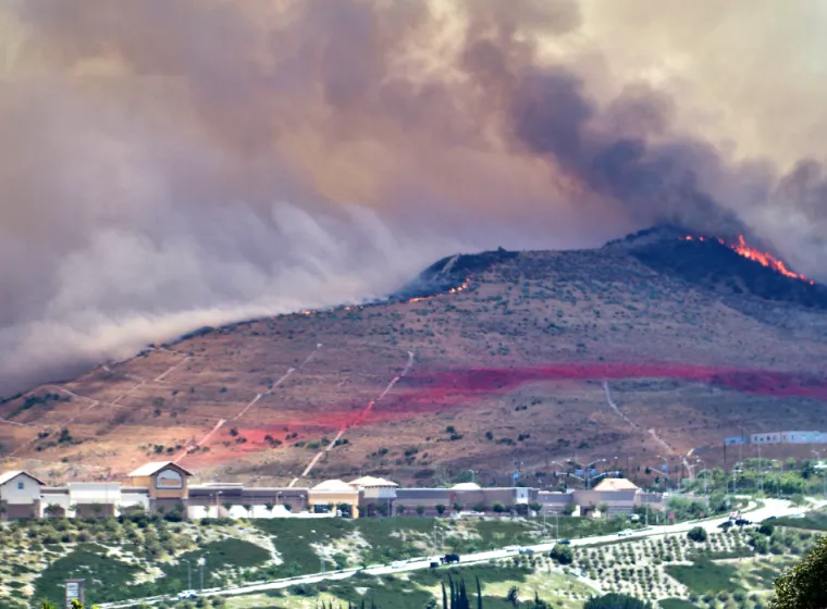 A controlled fire burns on the ridge of a foothill marked for fire management above a town